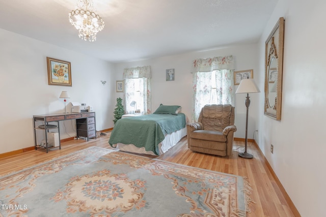 bedroom featuring an inviting chandelier, wood finished floors, and baseboards