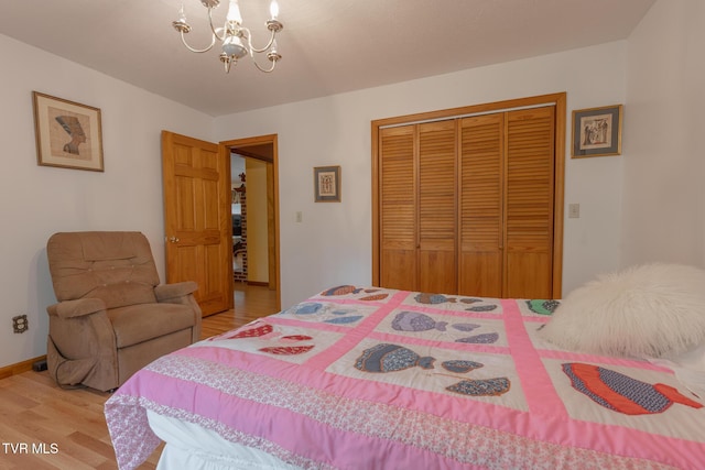 bedroom featuring an inviting chandelier, a closet, wood finished floors, and baseboards