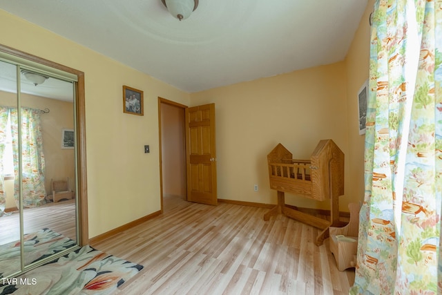 bedroom featuring a closet, light wood-style flooring, and baseboards