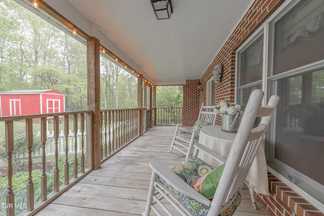 wooden terrace featuring a porch, an outdoor structure, and a shed