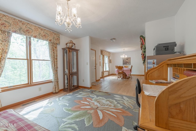 entryway with light wood-style floors, a healthy amount of sunlight, an inviting chandelier, and visible vents