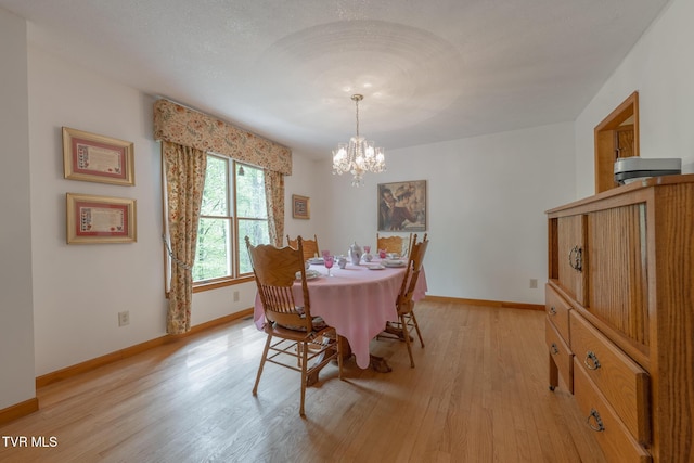 dining area featuring baseboards, light wood finished floors, and an inviting chandelier