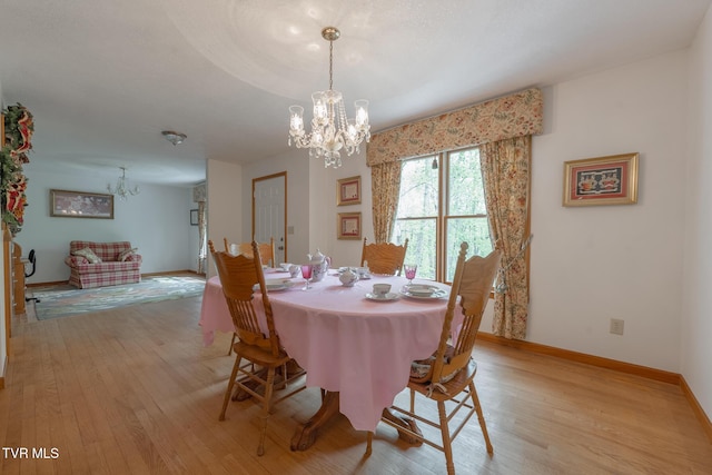 dining area featuring an inviting chandelier, light wood-type flooring, and baseboards