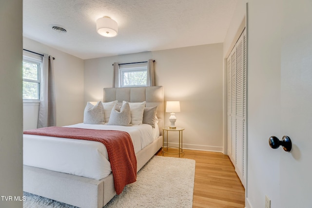 541 Vance Dr, Bristol, TN 37620 - bedroom featuring multiple windows, light wood-style floors, a closet, baseboards, and a textured ceiling