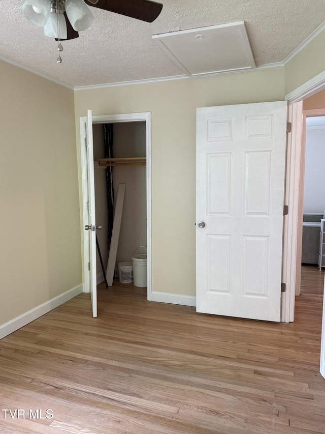 unfurnished bedroom with crown molding, a textured ceiling, light wood-style flooring, and a closet