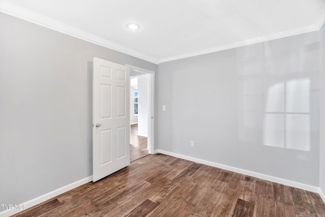 unfurnished room with crown molding, baseboards, and dark wood finished floors