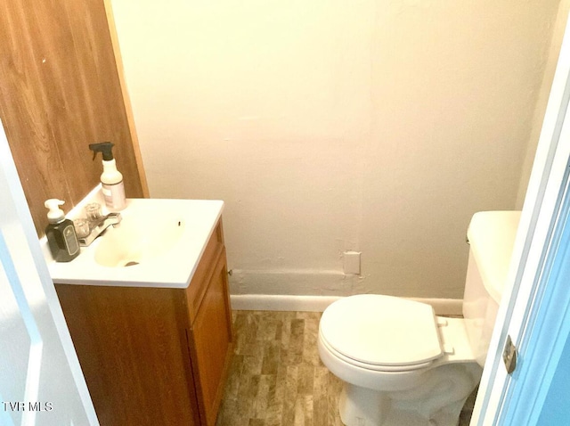 bathroom featuring toilet, baseboards, and vanity