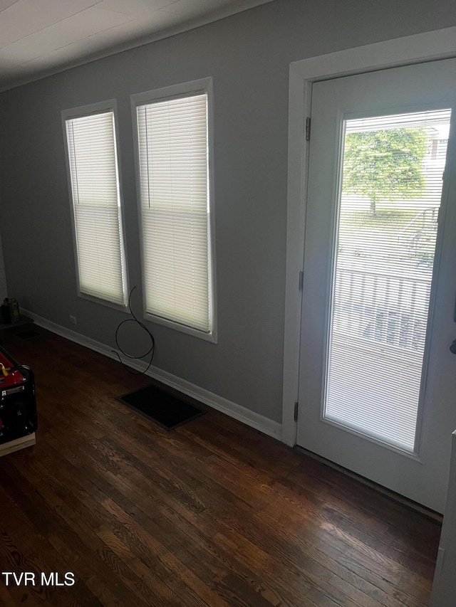 unfurnished room with baseboards, dark wood-style floors, and visible vents