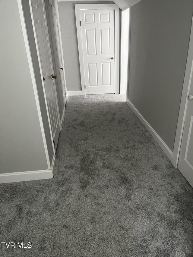 corridor with baseboards and carpet