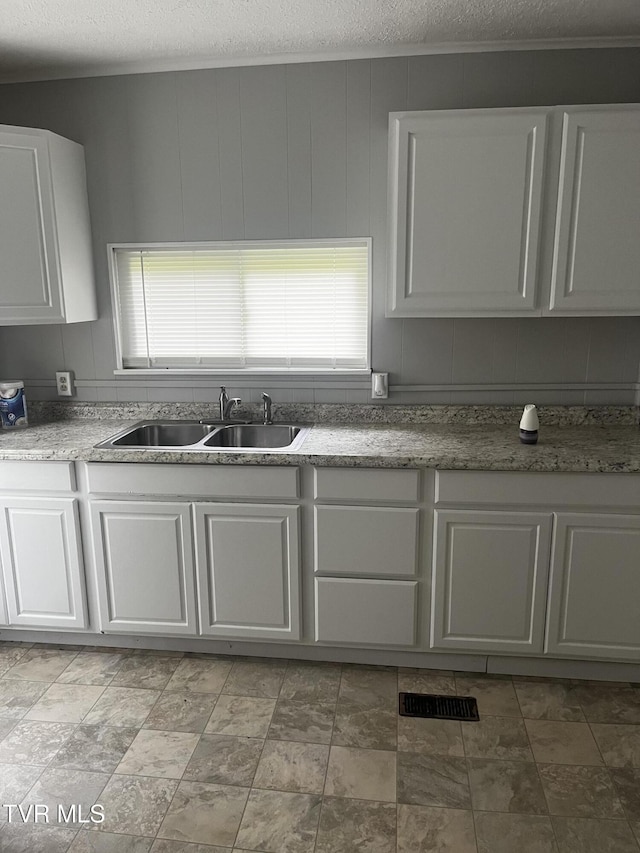 kitchen featuring a sink, a textured ceiling, and white cabinets