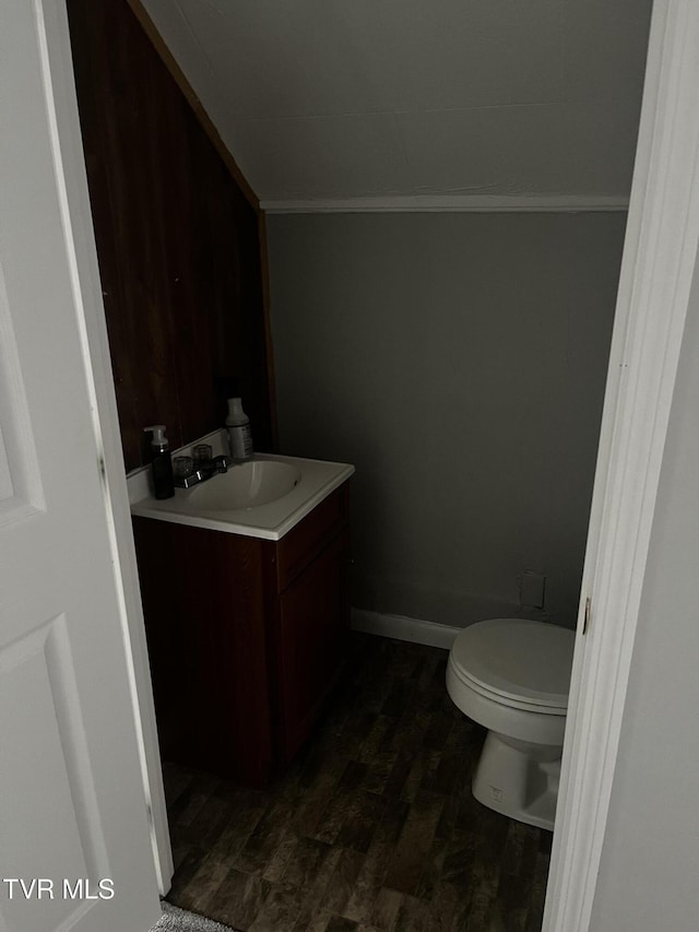 bathroom with toilet, baseboards, ornamental molding, vanity, and wood finished floors