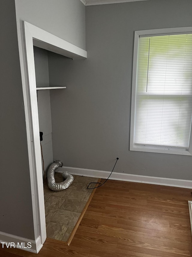 laundry room featuring baseboards, crown molding, and wood finished floors