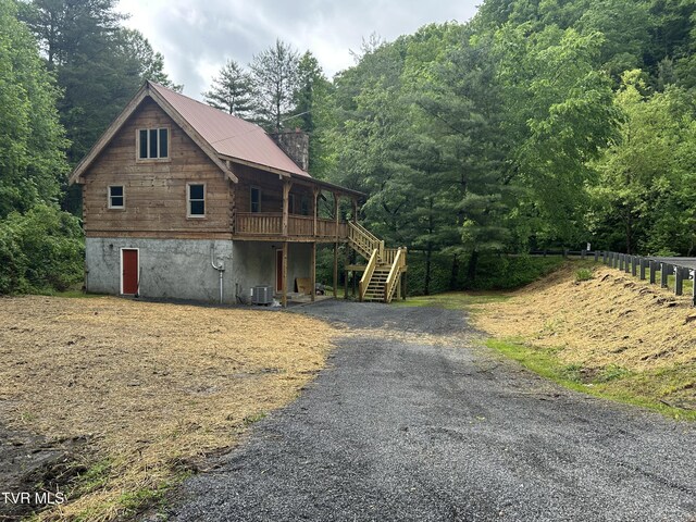 4406 Lawson Hollow Rd, Coeburn, VA 24230 - view of front facade featuring stairway, central air condition unit, a chimney, a wooded view, and log siding