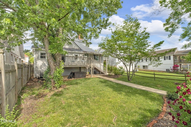 back of property featuring a lawn, stairway, a wooden deck, and fence