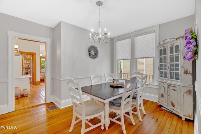 dining room with an inviting chandelier, a wealth of natural light, light wood finished floors, and visible vents