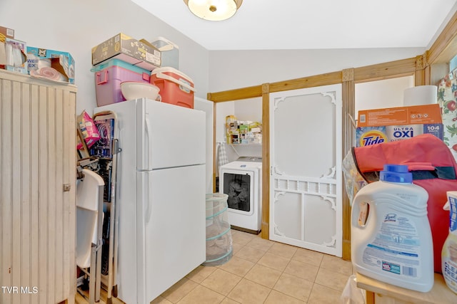 kitchen with vaulted ceiling, freestanding refrigerator, light tile patterned flooring, and washer / clothes dryer