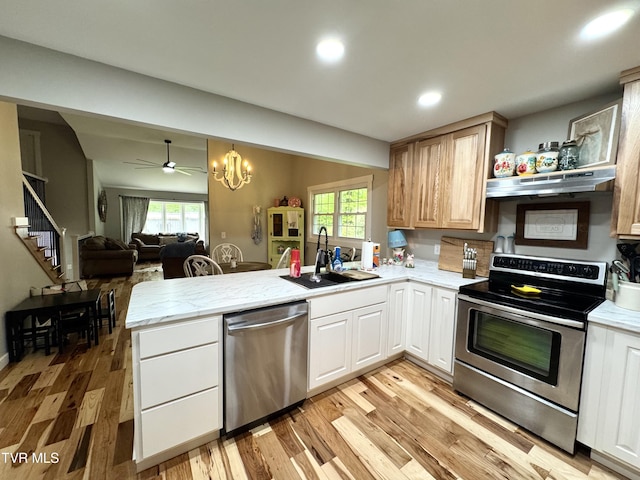 3401 Fairfax Rd, Coeburn, VA 24230 - kitchen with stainless steel appliances, under cabinet range hood, a peninsula, a sink, and light wood-type flooring