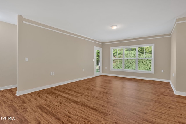 unfurnished room featuring wood finished floors, baseboards, and ornamental molding