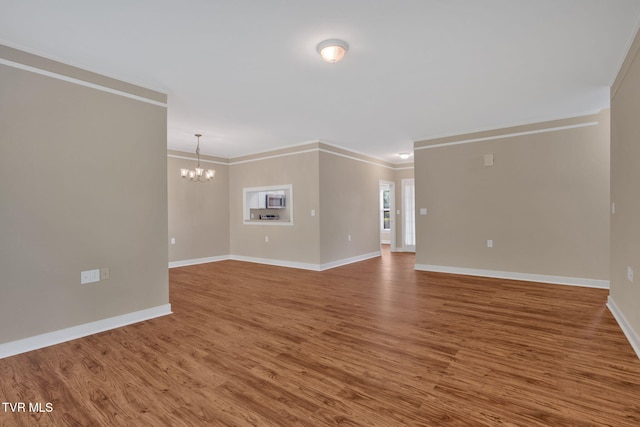 interior space with a chandelier, crown molding, baseboards, and wood finished floors