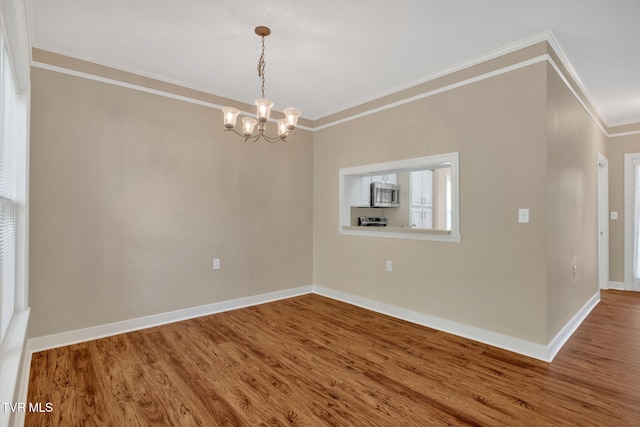 unfurnished room with crown molding, wood finished floors, baseboards, and a notable chandelier