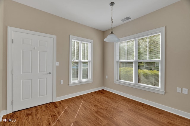 unfurnished dining area with baseboards, visible vents, and wood finished floors