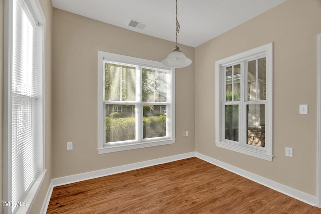 unfurnished dining area featuring visible vents, wood finished floors, and baseboards
