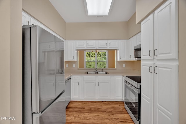 kitchen featuring white cabinetry, light wood finished floors, appliances with stainless steel finishes, and a sink