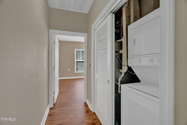 laundry room featuring baseboards, visible vents, wood finished floors, laundry area, and stacked washer / drying machine