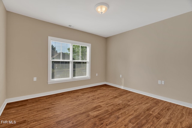 spare room featuring baseboards, visible vents, and wood finished floors