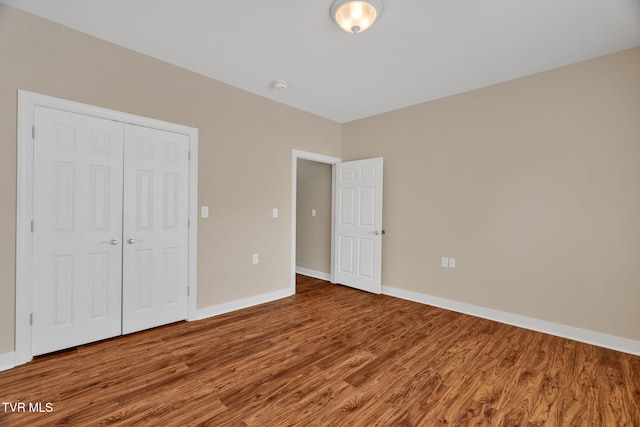 unfurnished bedroom featuring baseboards, a closet, and wood finished floors
