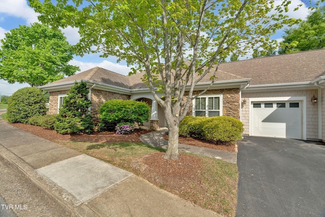 ranch-style home with roof with shingles, an attached garage, and driveway