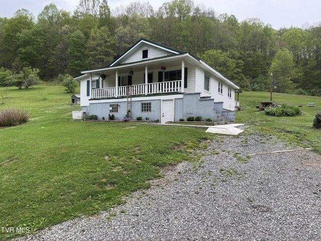 7311 Rocky Fork Rd, Wise, VA 24293 - farmhouse with gravel driveway, a porch, a view of trees, and a front lawn
