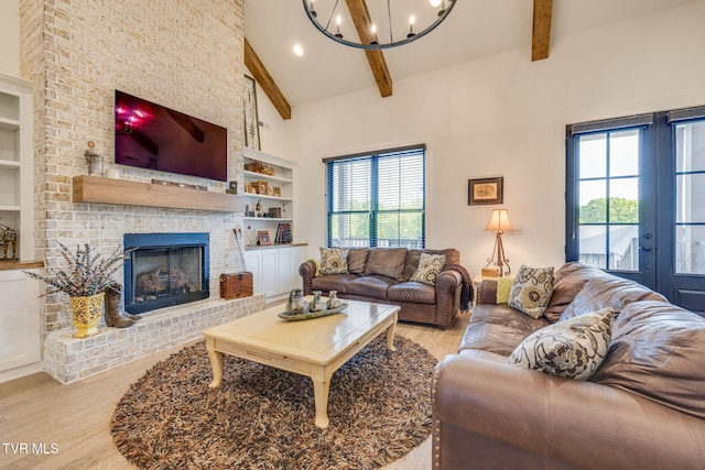 living area featuring light wood-style flooring, a chandelier, built in shelves, a brick fireplace, and recessed lighting