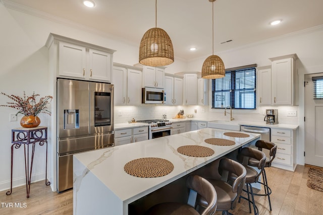 kitchen with stainless steel appliances, a sink, backsplash, a breakfast bar area, and crown molding
