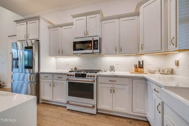 kitchen with appliances with stainless steel finishes, backsplash, crown molding, light wood-style flooring, and light stone counters