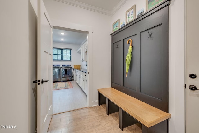 mudroom with crown molding, washing machine and dryer, and light wood finished floors
