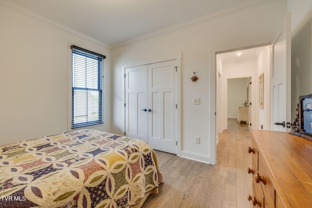 bedroom with light wood-style flooring, ornamental molding, a closet, and baseboards