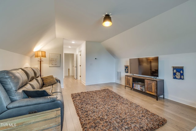 living room featuring vaulted ceiling, light wood finished floors, and baseboards