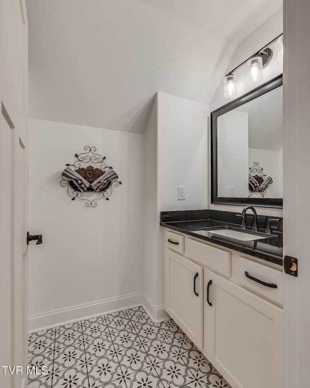 bathroom featuring vaulted ceiling, vanity, and baseboards