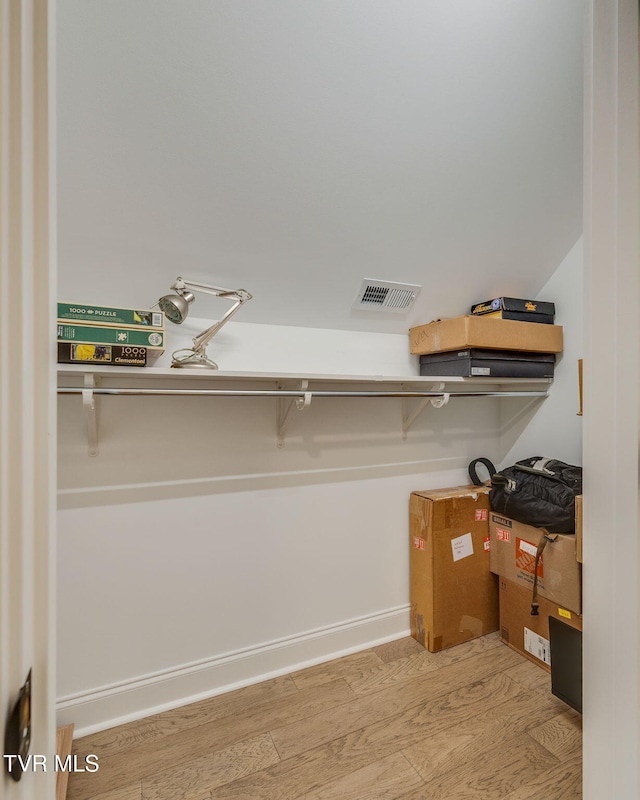 walk in closet with wood finished floors
