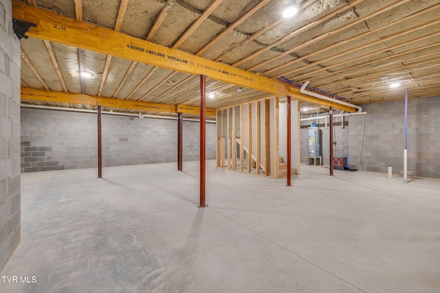 unfinished basement featuring water heater and concrete block wall