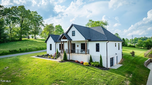 modern inspired farmhouse featuring an attached garage, a front yard, roof with shingles, and board and batten siding
