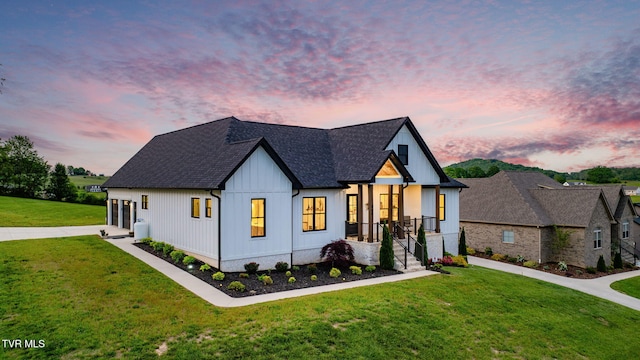 modern farmhouse style home featuring a front yard, driveway, board and batten siding, and roof with shingles