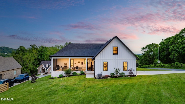 back of property at dusk featuring board and batten siding, a yard, and central AC