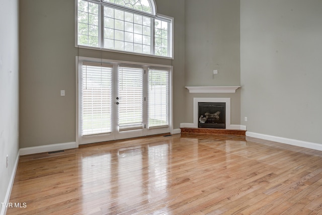 575 Boring Chapel Rd Unit 31, Johnson City, TN 37615 - unfurnished living room featuring baseboards, wood finished floors, a fireplace with raised hearth, and a high ceiling
