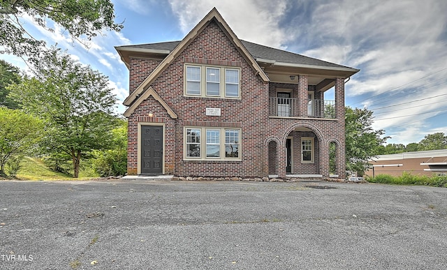 view of front of house featuring a balcony and brick siding