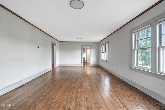 empty room featuring ornamental molding, baseboards, visible vents, and wood finished floors