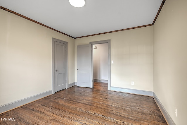 empty room with crown molding, dark wood-type flooring, and baseboards
