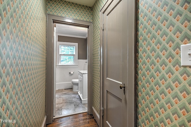 bathroom featuring wallpapered walls, toilet, baseboards, a wainscoted wall, and wood finished floors