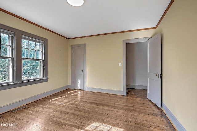 spare room with ornamental molding, baseboards, light wood-style flooring, and visible vents